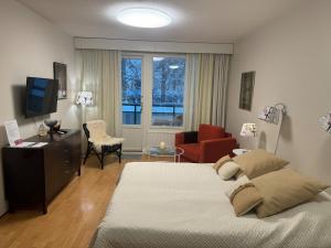 a bedroom with a bed and a tv and a chair at Kylpylä-hotelli 261 in Ikaalinen