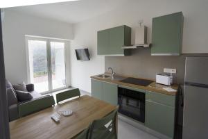 a kitchen with green cabinets and a wooden table at Il Vecchio Pozzo Apartments in Ostigliano