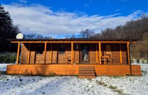 a wooden cabin in the snow with chairs and tables at Sauna v lese in Uhrovec
