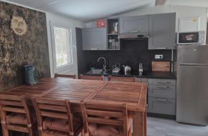 a kitchen with a wooden table and a stainless steel refrigerator at Sauna v lese in Uhrovec
