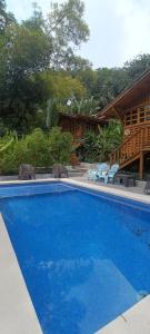 a large blue swimming pool next to a house at Cabañas Samara Buenavista in Sámara