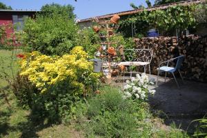 a garden with a table and chairs and flowers at LE Petit Ru 10 MN DE GIVERNY in Saint-Marcel +12 photos