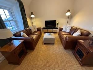 a living room with brown leather couches and a tv at Roods Apartment in Angus