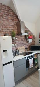 a kitchen with white appliances and a brick wall at Seaside Apartment in Moreton +21 photos
