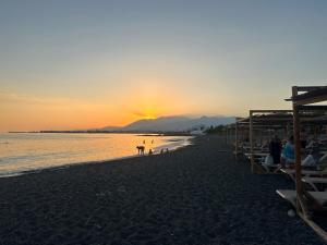 a beach with people and a dog at sunset at Villa Komorebi, the Private 3BR Grand Estate - 2500m2 Garden - Walk to Beach & Town in Ierapetra