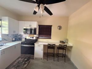 a kitchen with two bar stools and a ceiling fan at Cozy Nest in George Town +1 photo