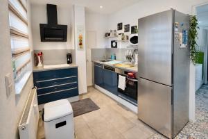 a kitchen with blue cabinets and a stainless steel refrigerator at 2 Room Galerie Einliegerwohnung in Rheinstetten, Messe Nähe, Rollstuhlfahrer geeignet in Rheinstetten