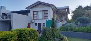 a white house with a garden in front of it at 1-On-Scott Garden Suites in Somerset East