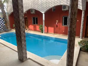 a swimming pool in a house with a red wall at Sall Africa Tourisme in Mbour +12 photos