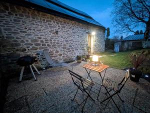 a patio with two chairs and a table with a light at Gîte du Portz in Ploërdut