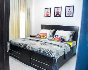 a bedroom with a bed with colorful pillows on it at 3Tee Serviced Apartment Abeokuta in Abeokuta