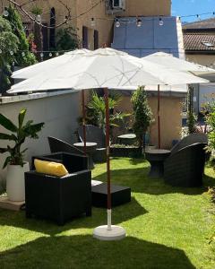 a white umbrella in the grass with chairs and tables at Café des Voyageurs Noës in Chalais