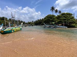 a boat sitting in the water on a beach at Letharo Residancies in Dodanduwa