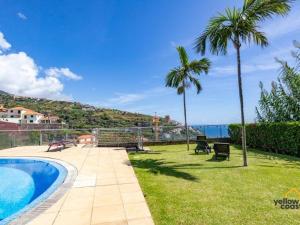 a backyard with a swimming pool and palm trees at Vista Calheta Apartment in Calheta