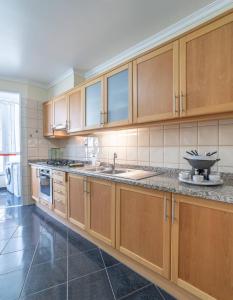 a large kitchen with wooden cabinets and a sink at Vista Calheta Apartment in Calheta