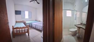 a bedroom with a bed and a bathroom with a sink at Linda Casa Mongagua COM 03 DORMS in Mongaguá +25 photos