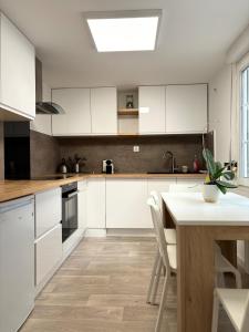 a kitchen with white cabinets and a table at Charmant Duplex - Hyper Centre - 44m2 - Proche Place Stanislas in Nancy