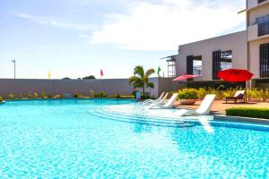 a pool with chairs and umbrellas next to a building at Cara Studio Mactan Cebu Cozy with Garden View at Primeworld District Tower H 103 in Lapu Lapu City