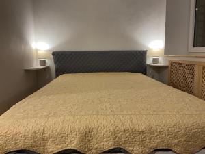 a bed in a room with two lights on two tables at Гнёздышко in Visaginas