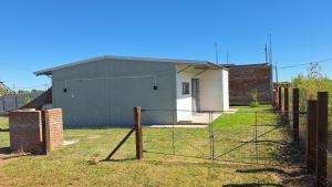 a fence in front of a house with a building at Nyumba in Colonia Nuevo Paysandú +1 photo