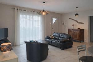 a living room with a leather couch and a tv at Gite Lagarrigue in Lavaur