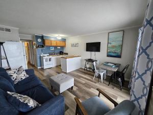 a living room with a blue couch and a kitchen at BEACHSIDE CONDO-WATER AND POOL VIEW Top Floor in Tybee Island
