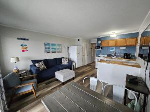 a living room with a blue couch and a kitchen at BEACHSIDE CONDO-WATER AND POOL VIEW Top Floor in Tybee Island