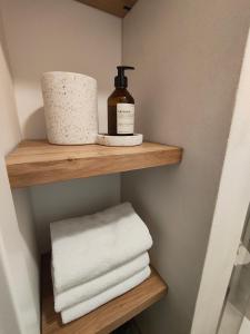 a bathroom shelf with towels and a bottle of soap at Apartments 11 in Forchheim +3 photos