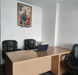 a desk with a laptop in a room with chairs at Hotel O Daffodils in Gurgaon