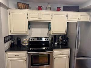 a kitchen with white cabinets and a stainless steel refrigerator at Gated Lakefront Retreat in Edmond