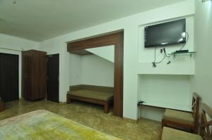 1 dormitorio con TV en la pared y banco en Lago villa en Bhopal