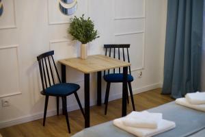 a table with two chairs and a vase with a plant on it at Dan Apartament C, Self check-in in Opole
