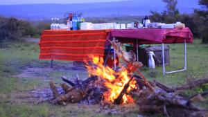 a picnic table with a blanket over a fire at Mara Balanite Hotel in Masai Mara