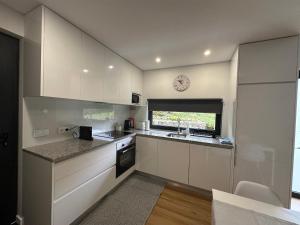 a kitchen with white cabinets and a clock on the wall at Ri&Vale Alojamentos in Vieira do Minho