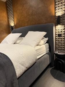 a bed with white sheets and pillows on it at Les Suites in Strasbourg