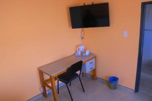 a desk with a chair and a television on a wall at Bataung Guest House in Mafeteng