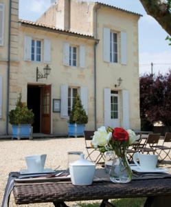 a table with a vase of flowers and a building at Les chambres du Domaine Rollan de By in Bégadan