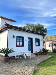 a white house with two chairs and a table at Cadivó Chalé Lavras Novas in Ouro Preto