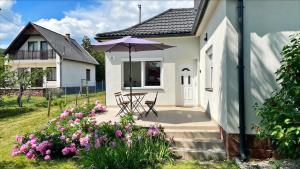 a house with a patio with an umbrella and flowers at Alma2 Vendégház in Révfülöp +5 photos