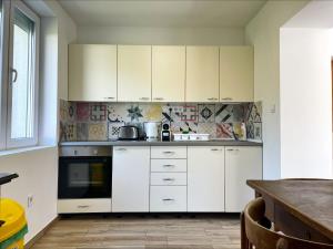 a white kitchen with white cabinets and a table at Alma2 Vendégház in Révfülöp
