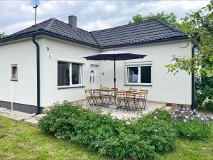 a white house with chairs and an umbrella at Alma2 Vendégház in Révfülöp