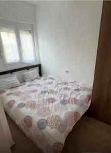 a bedroom with a bed with a comforter and two windows at Block and Svemir Suiets in Kumanovo