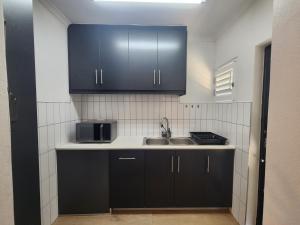 a kitchen with black cabinets and a sink at Welgelegen Self Catering in Malmesbury