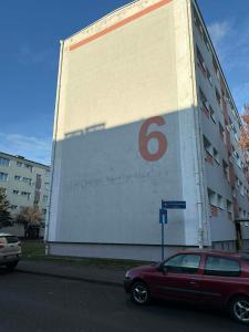 a large building with a red car parked in front of it at Leo Apartament in Konin