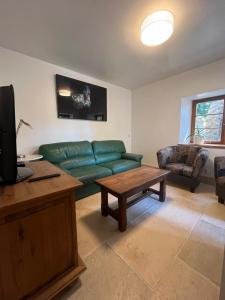 a living room with a green couch and a table at Moulin Cottage - Germaines in Germaines