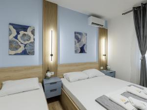 two beds in a bedroom with white sheets and blue walls at Avenue Apartments Ilinden in Ilinden