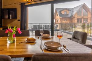 a wooden table with two glasses of wine on it at TRIA House Liptov in Ižipovce