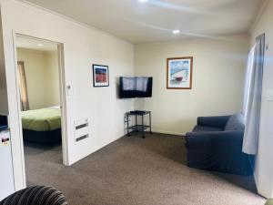 a living room with a couch and a bed and a mirror at Bassingers Motor Lodge in Levin