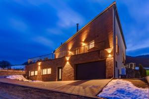 a brick building with a garage at night at TRIA House Liptov in Ižipovce