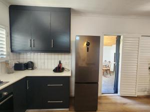 a kitchen with black cabinets and a stainless steel refrigerator at Welgelegen Self Catering in Malmesbury
